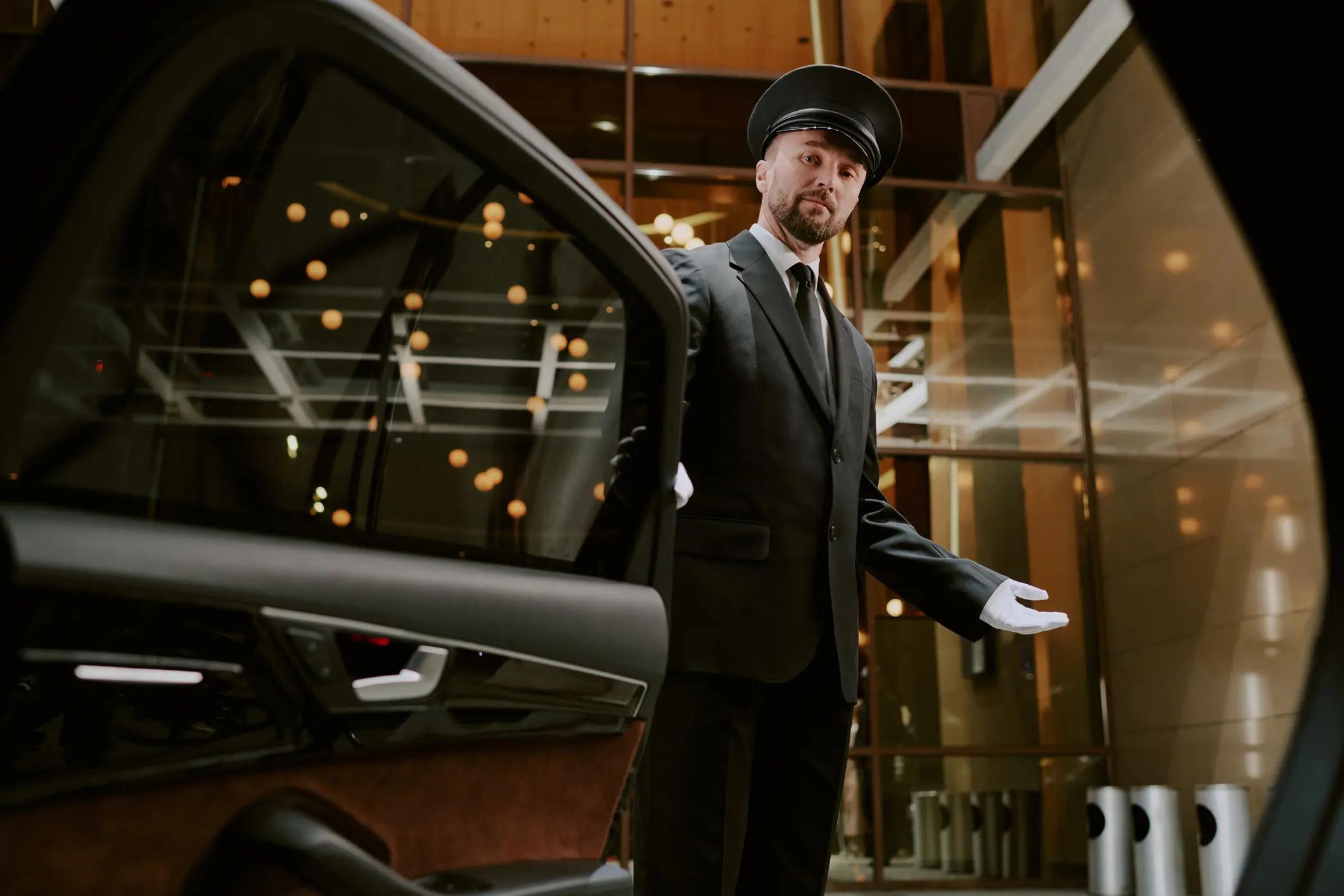 Chauffeur in cap and white gloves welcoming a guest into a luxury vehicle in Park City, Utah