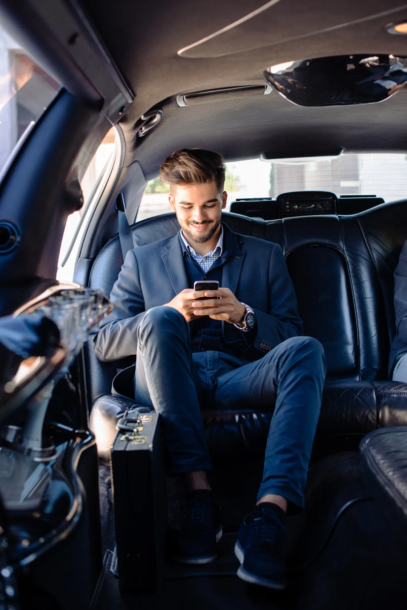 Passenger relaxing on his phone in a limousine during a private car service ride from Salt Lake City Airport to Park City